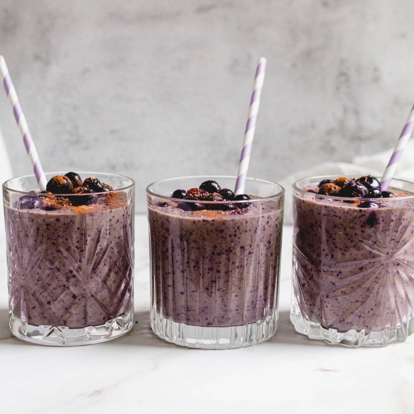 Blueberry banana smoothie with frozen bananas, blueberries, and spinach blended in a glass with blueberries on top. 