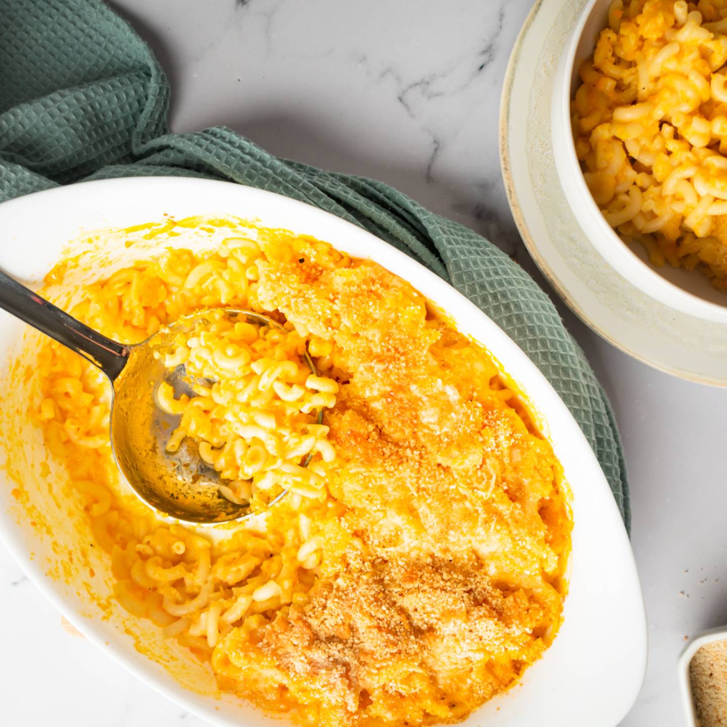 Cheddar carrot macaroni and cheese in a baking dish with crispy breadcrumbs on top.