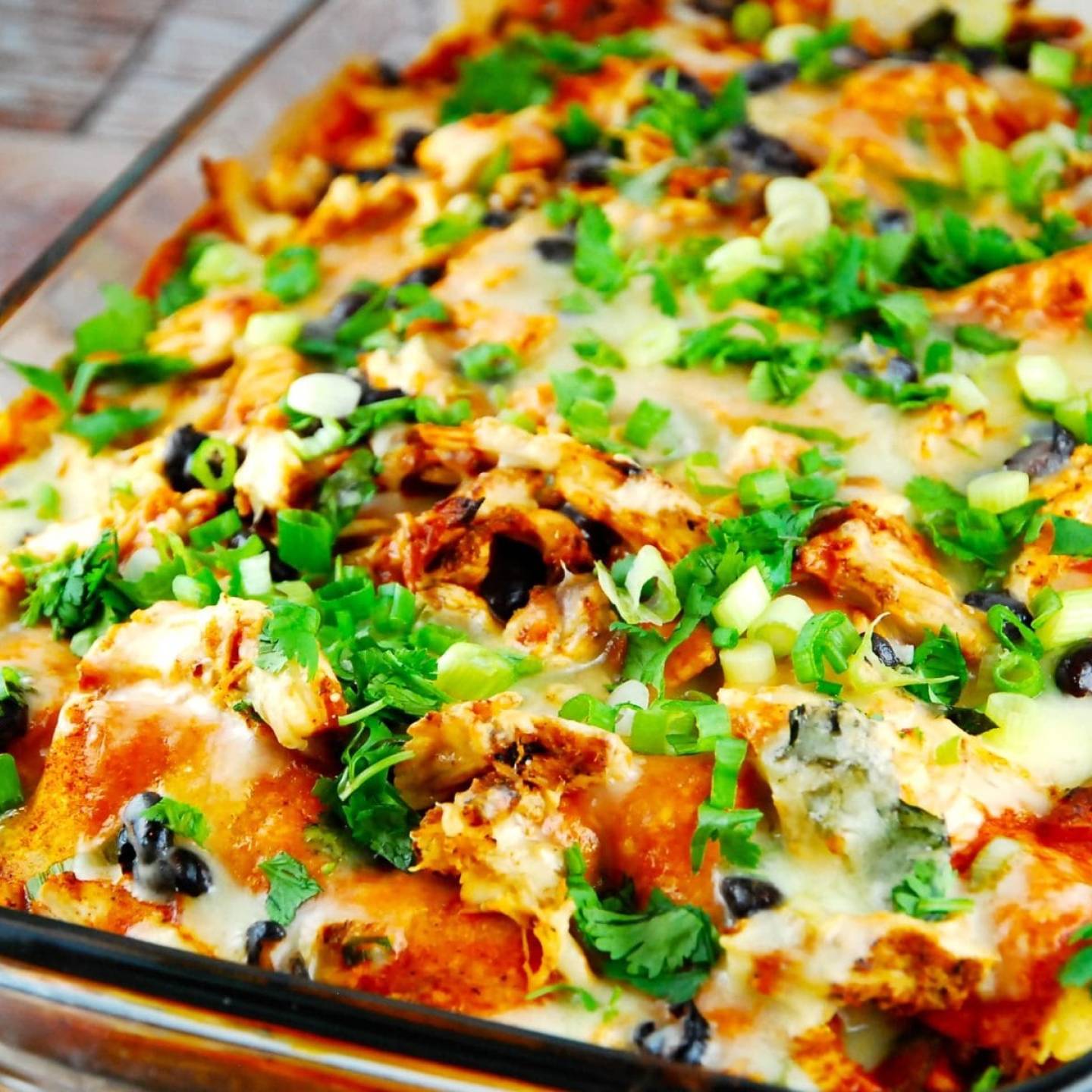 Chicken Enchilada Casserole Chicken enchilada casserole with green onions and olives in a baking dish.