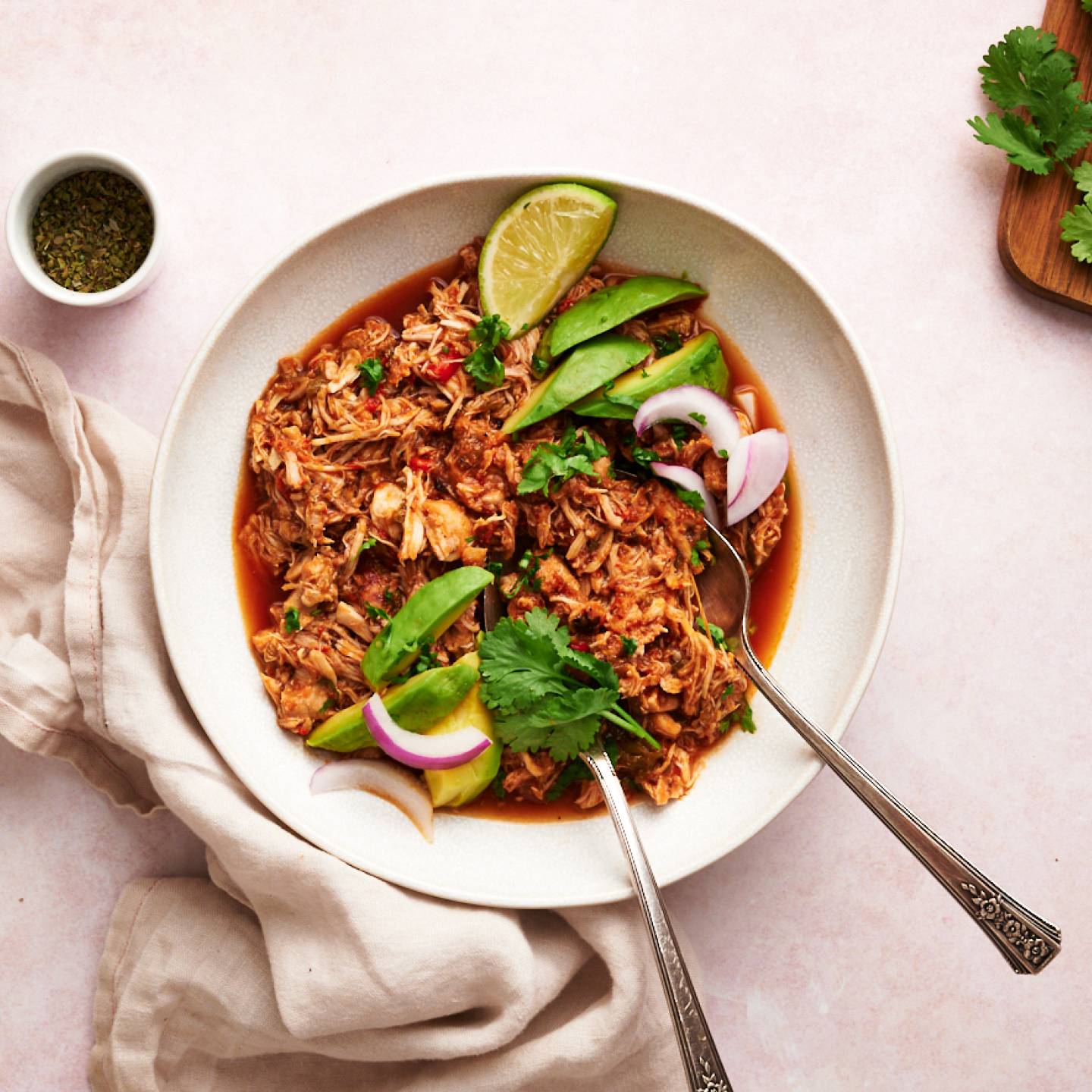Chicken machaca served in a bowl with shredded chicken in spicy tomato sauce with limes and red onion.