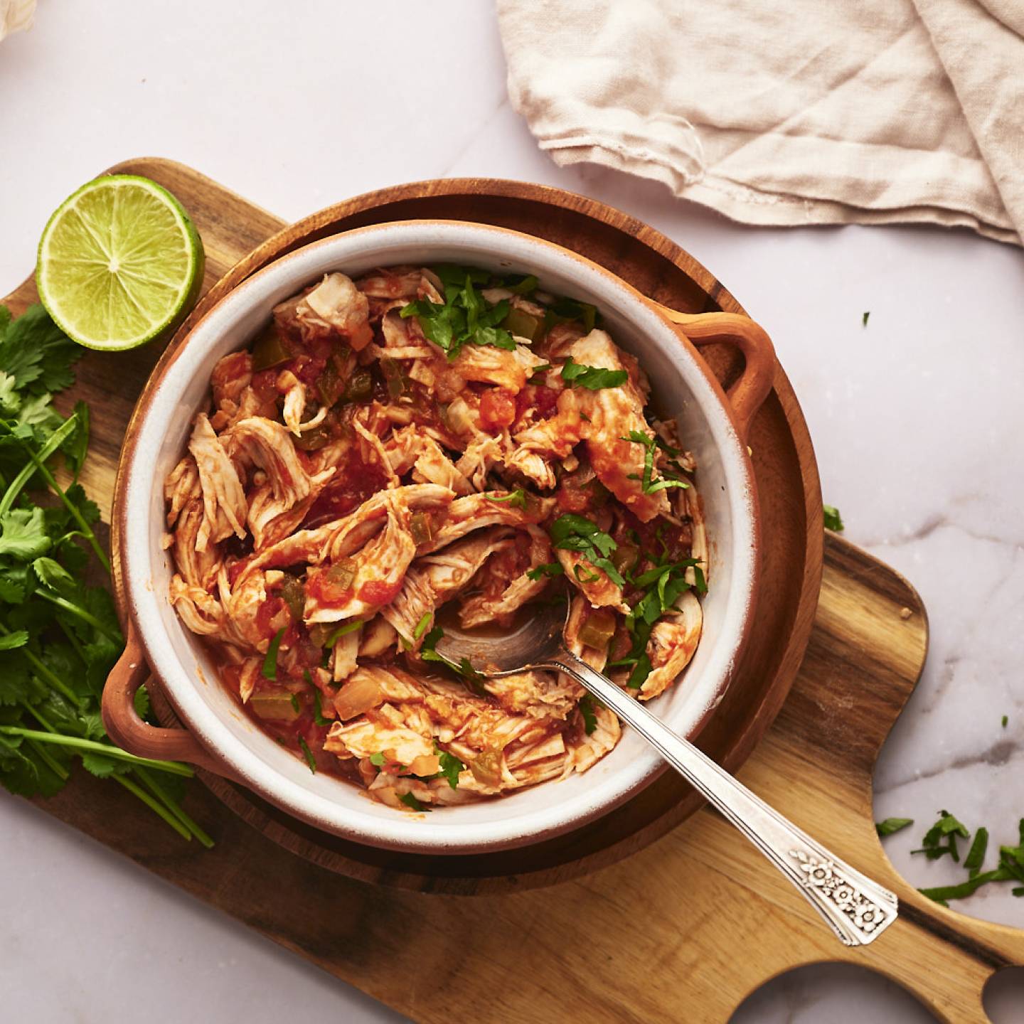 Chicken tinga in a bowl with onions, cilantro, avocado, and queso fresco.