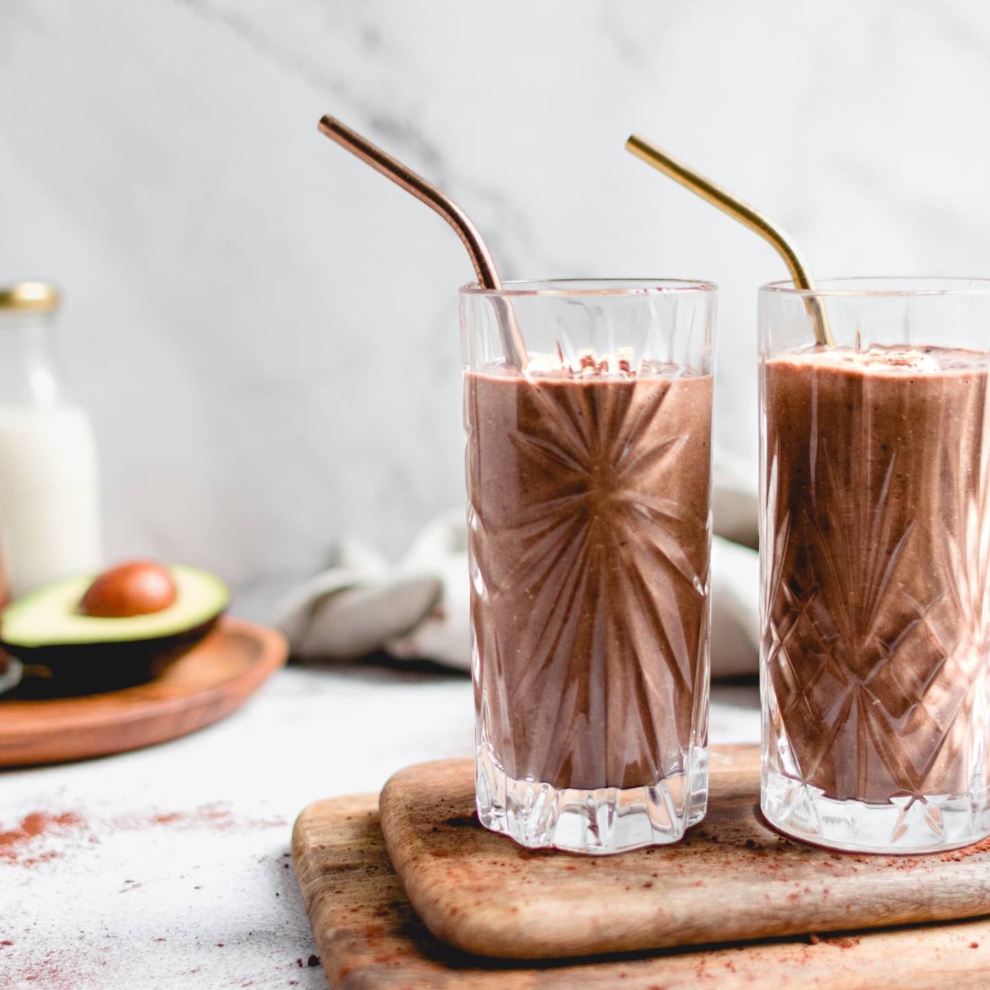 Chocolate avocado smoothie in a glass with blended avocado, banana, cocoa powder, chia seeds, and more.