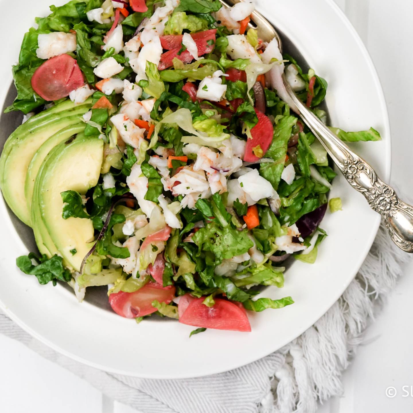 Chopped shrimp salad with fresh herbs, avocado, and a lemon vinaigrette in a bowll.