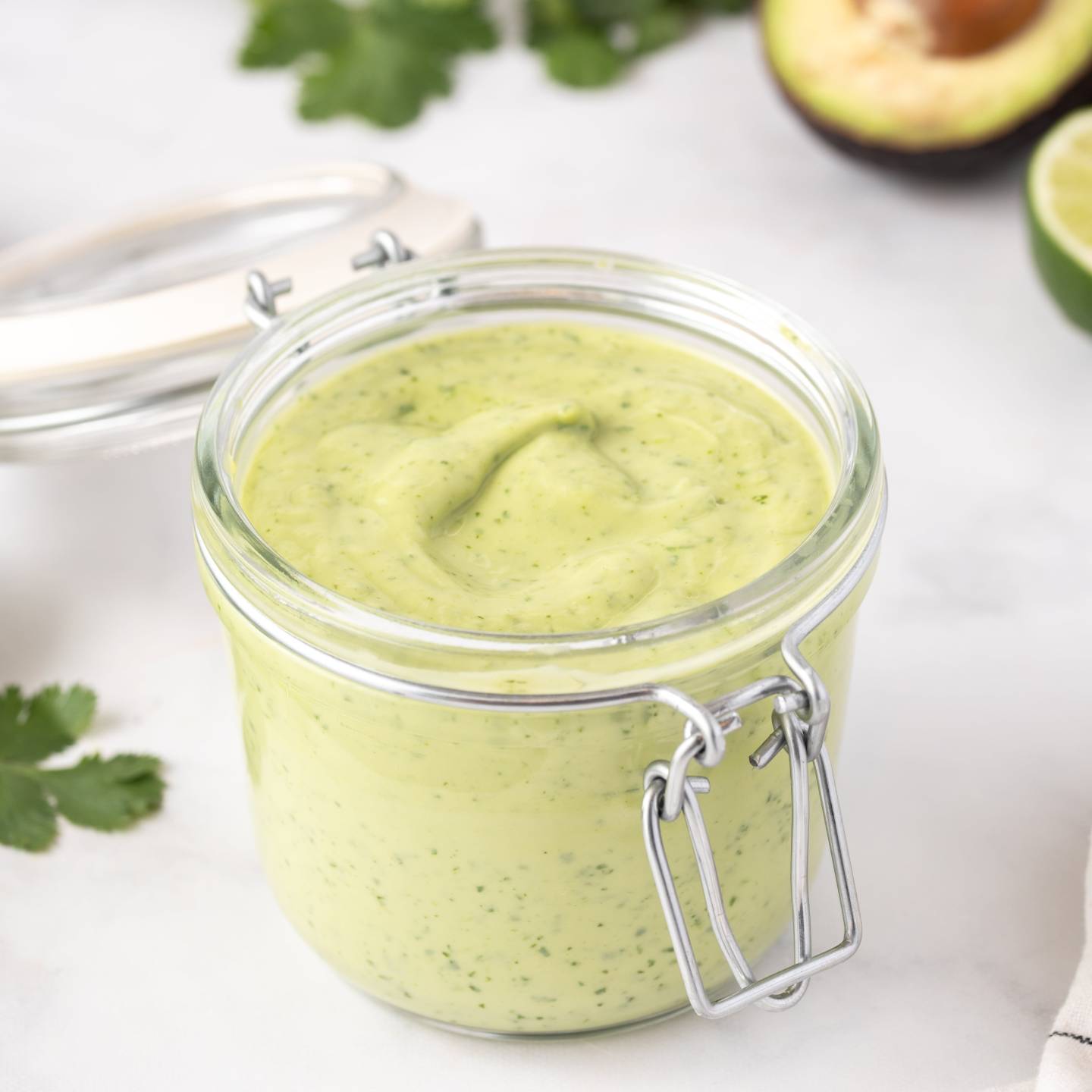Creamy avocado dressing made with avocado, Greek yogurt, cilantro, lime juice, and garlic in a small glass jar.