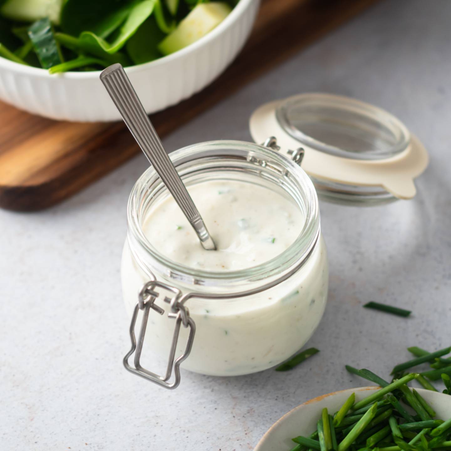 Creamy gorgonzola dressing with chunks of gorgonzola cheese, Greek yogurt, chives, and buttermilk in a small glass jar.