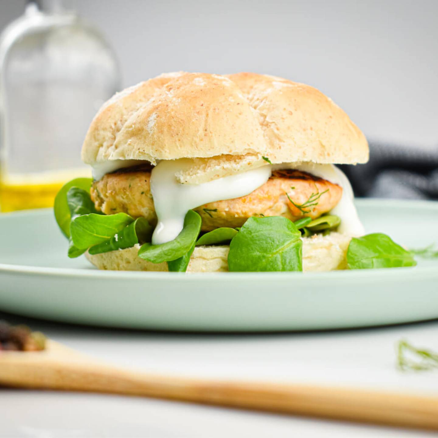 Dill Salmon Burgers with yogurt sauce and dressing on a whole wheat bun.