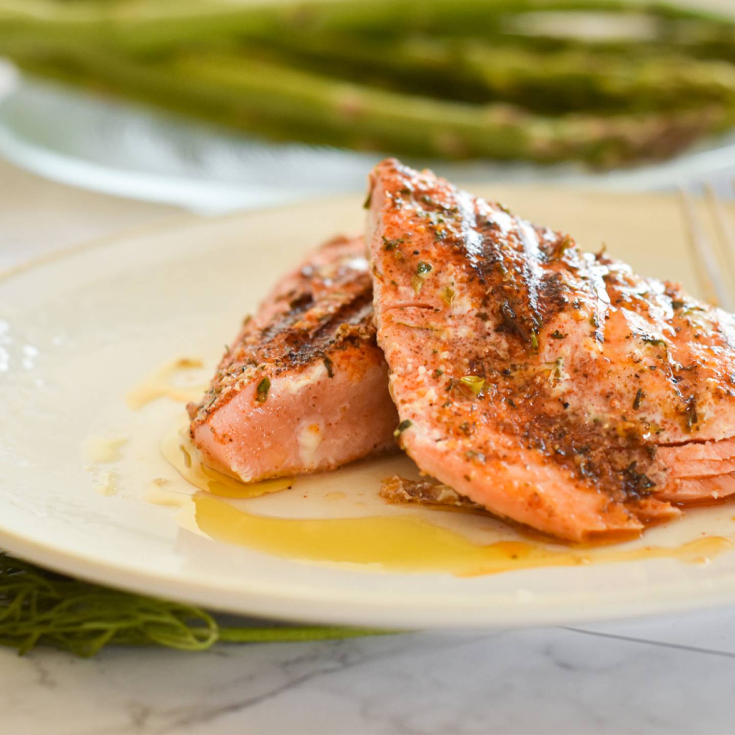 Grilled salmon with a Cajun spice rub on a plate with asparagus and salad./