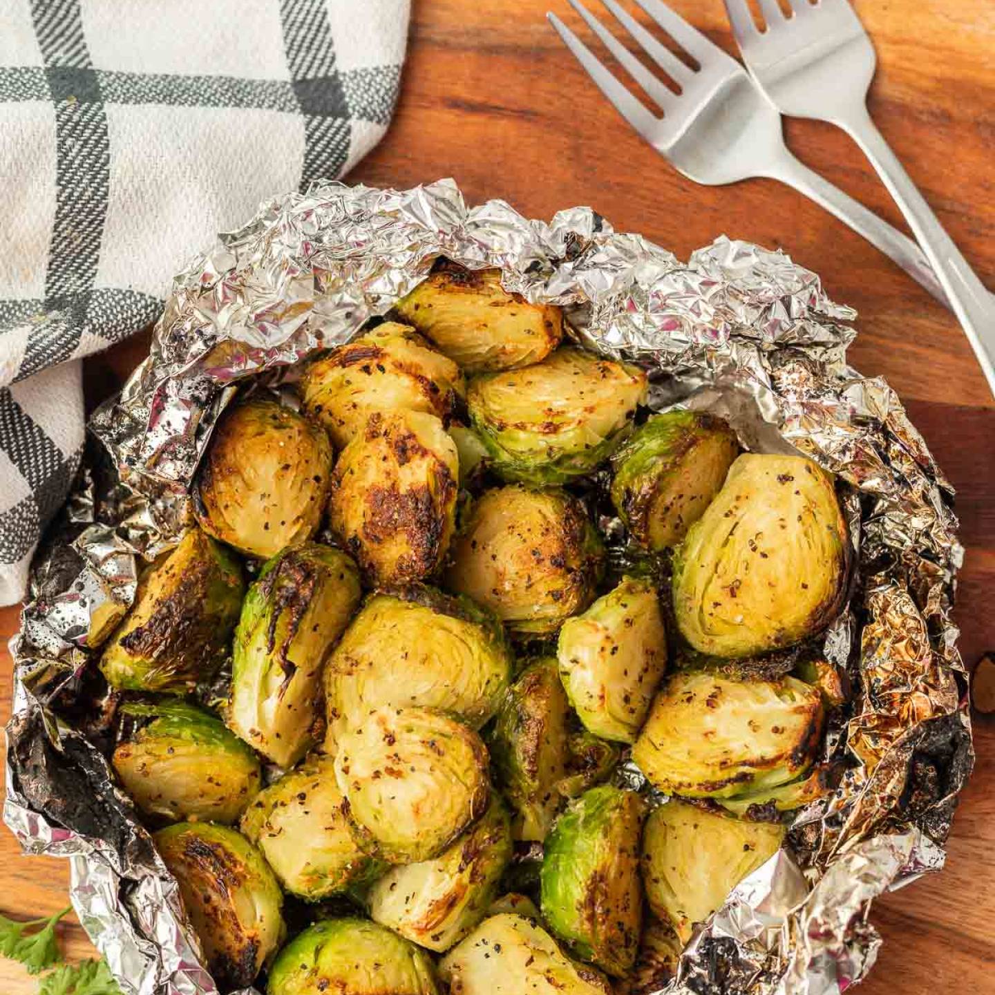 Grilled Brussel Sprouts in Foil on a wooden table.