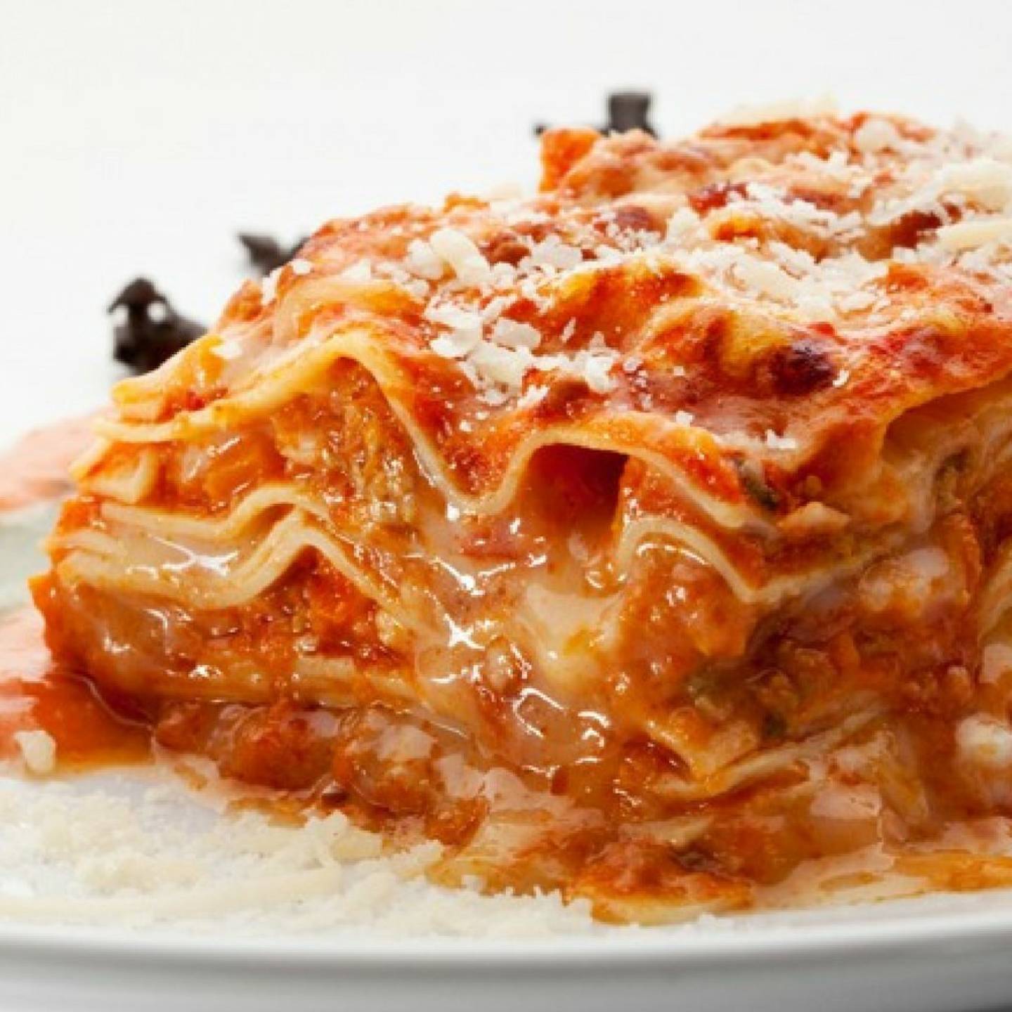 Chicken Parmesan lasagna with ricotta cheese and cooked chicken on a plate.