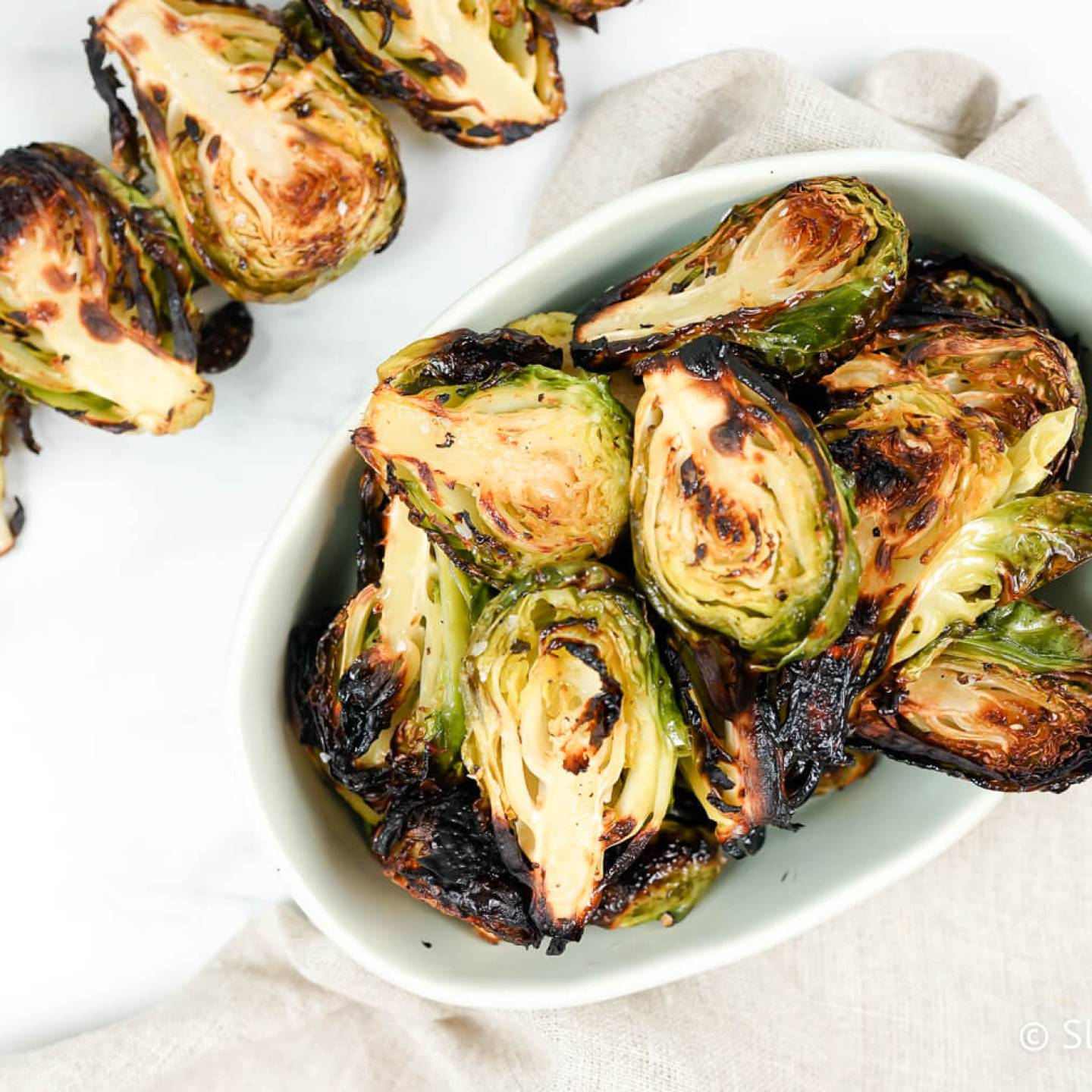Grilled Brussel Sprouts on a skewer and in a bowl with grill marks.