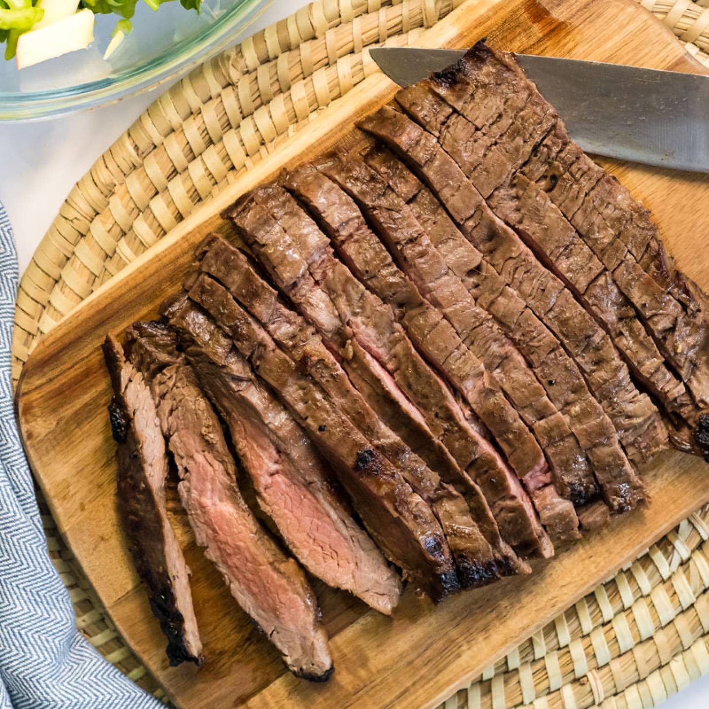 Grilled flank steak on a cutting board with a knife.