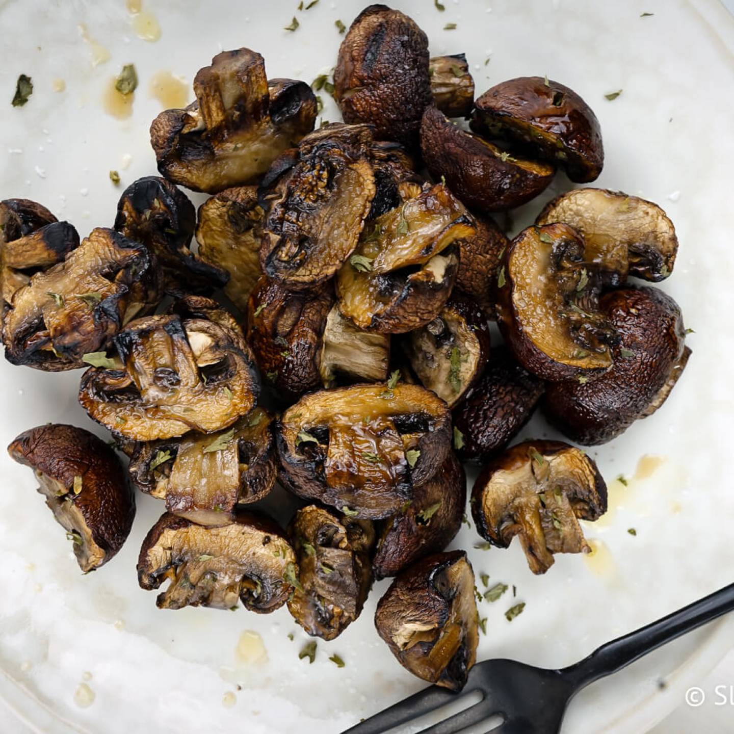 Grilled mushrooms with balsamic vinegar, olive oil, and garlic on a plate.