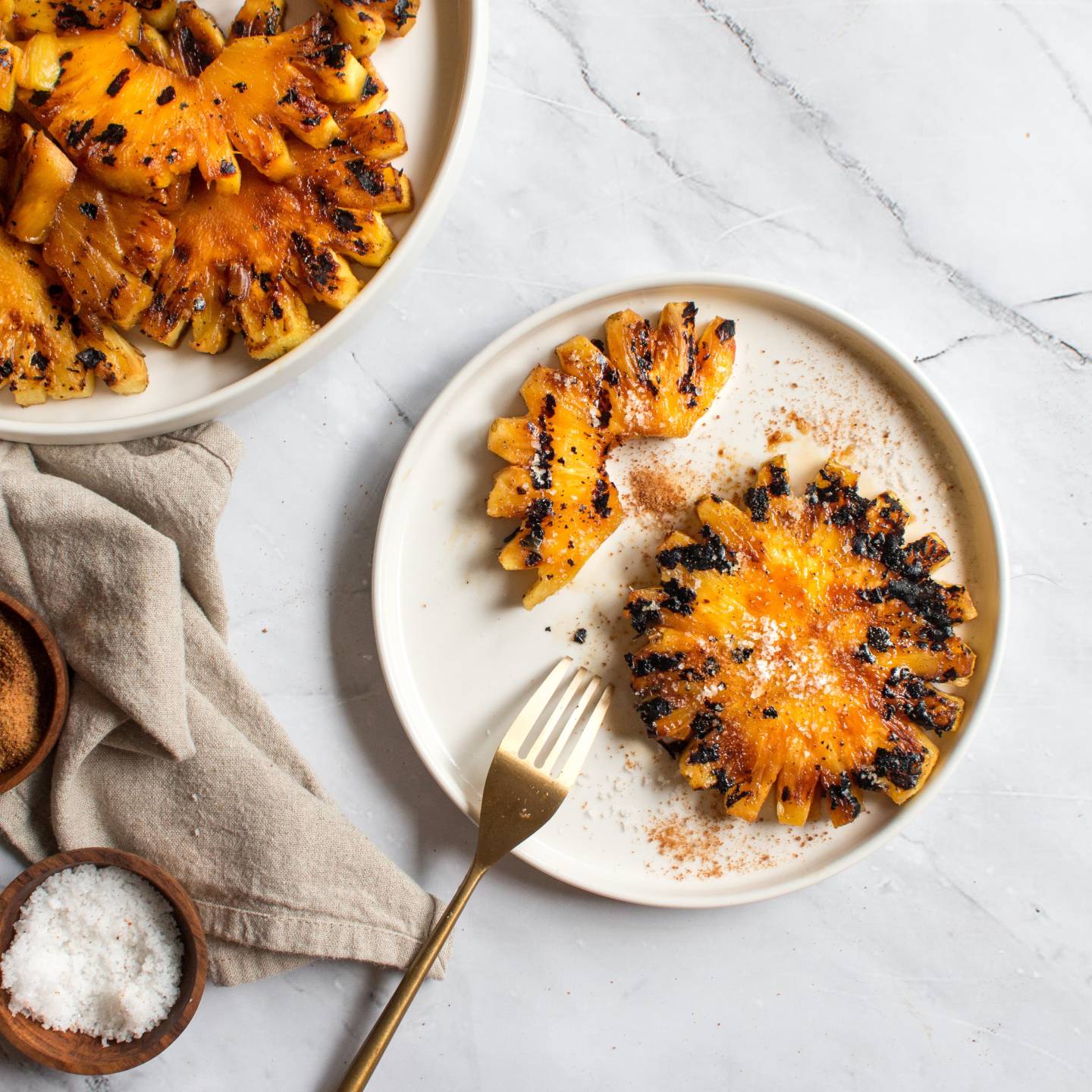 Grilled pineapple with brown sugar and flaky sea salt on a plate. 