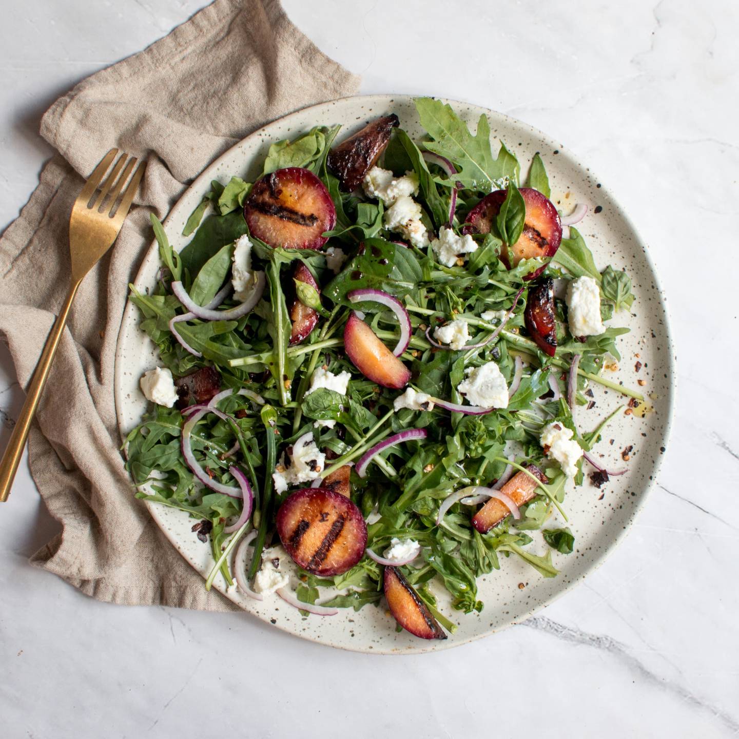 Grilled plum salad with arugula, grilled plums, red onions, goat cheese, and fresh herbs. 
