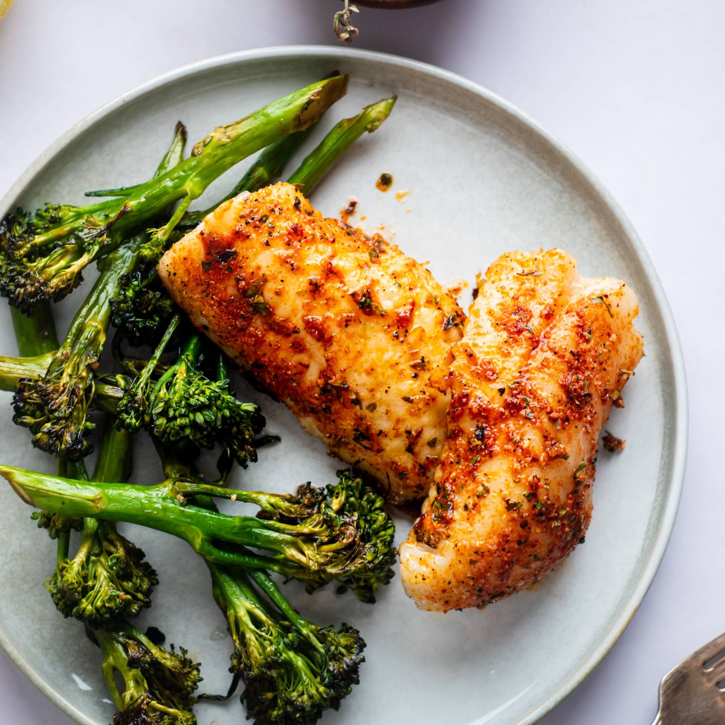 Grilled red snapper with homemade spice rub on a plate with grilled broccoli.