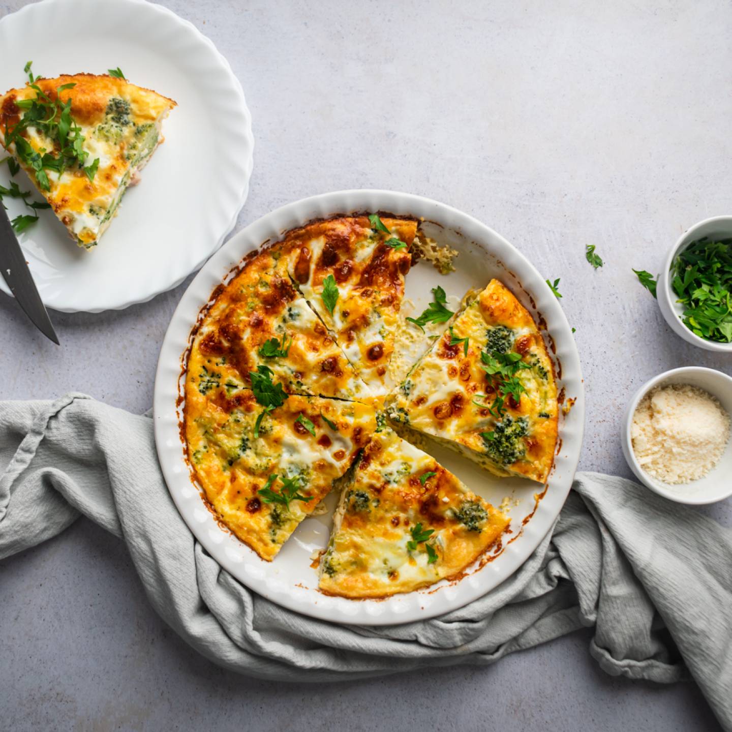 Ham and cheese frittata with broccoli cooked in a pie dish with a slice cut on the side. 