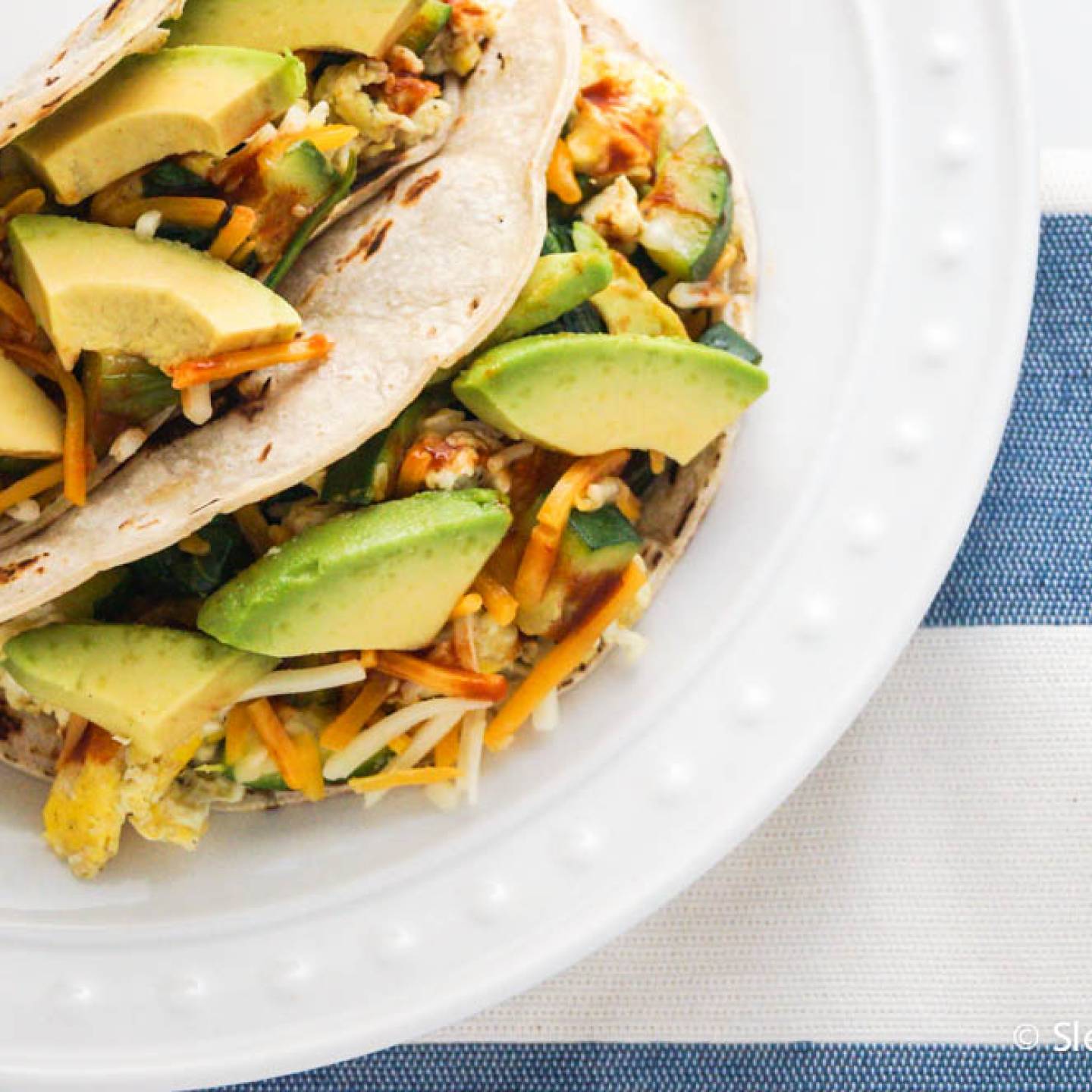 Healthy breakfast tacos with black beans, eggs, avocado, and salsa in corn tortillas.