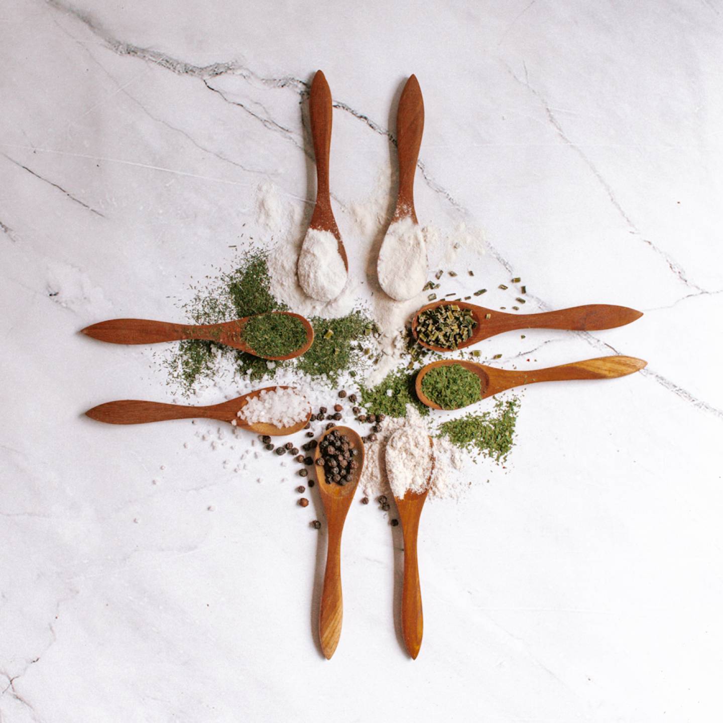 Homemade ranch seasoning in small wooden spoons with dried herbs, buttermilk powder, salt, and pepper.