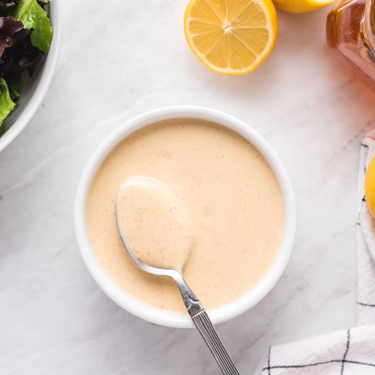 Honey mustard  with Greek yogurt, honey, and Dijon mustard in a small bowl with green salad on the side.
