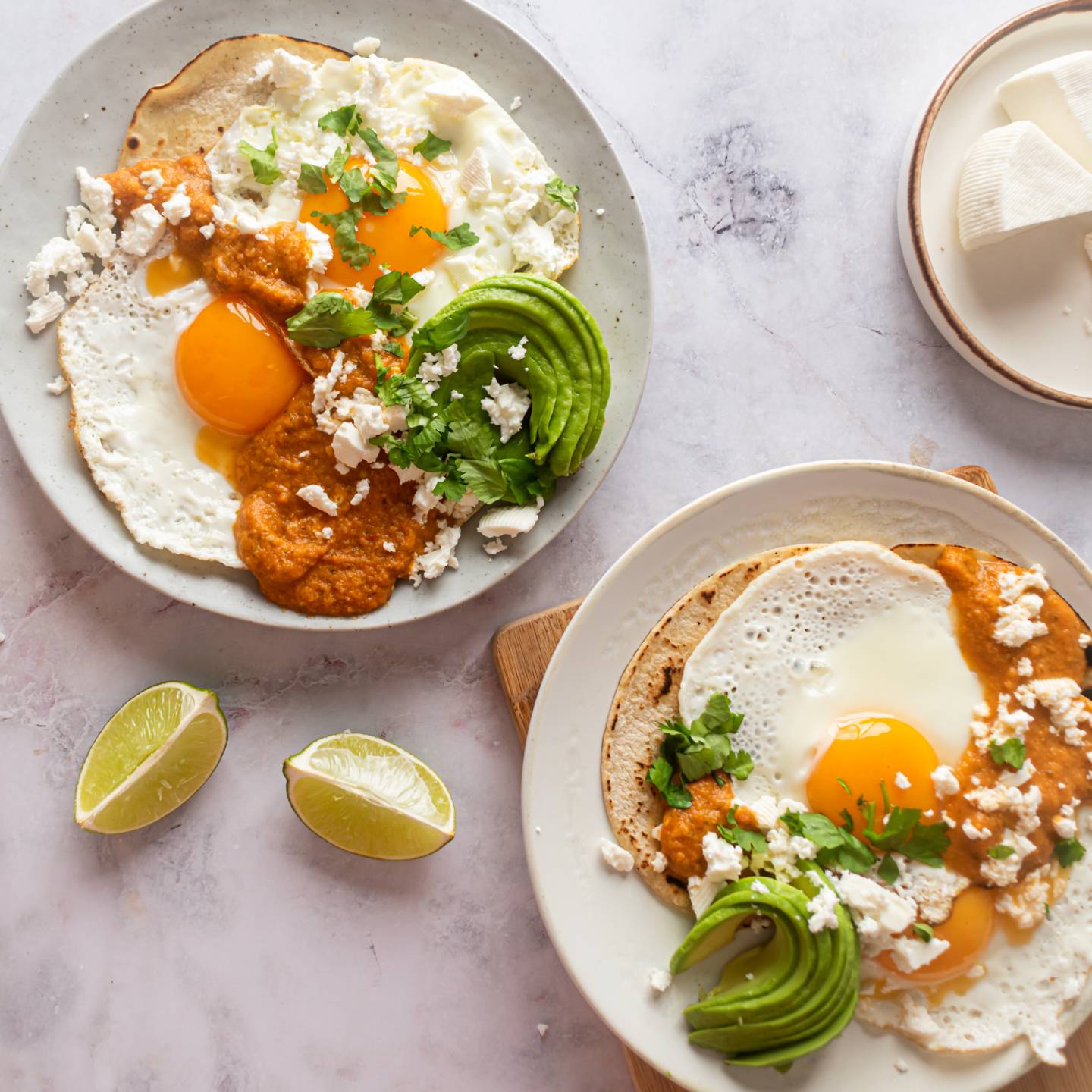 Huevos rancheros with sunny side up eggs served on corn tortillas with ranchero sauce, avocado, and cheese.