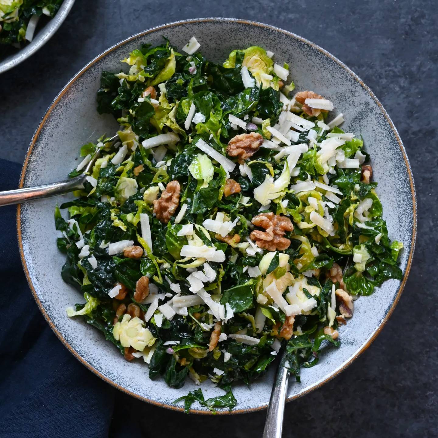 Kale and Brussels sprout salad with walnuts, Parmesan and lemon mustard dressing on a serving plate.