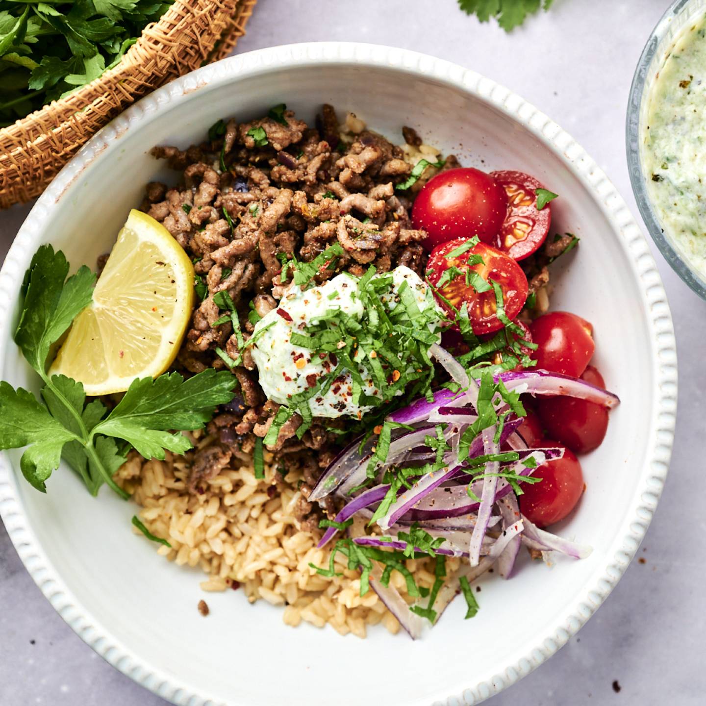 Kofta ground beef bowls with seasoned ground beef, brown rice, red onion, tomatoes, parsley, and cherry tomatoes.