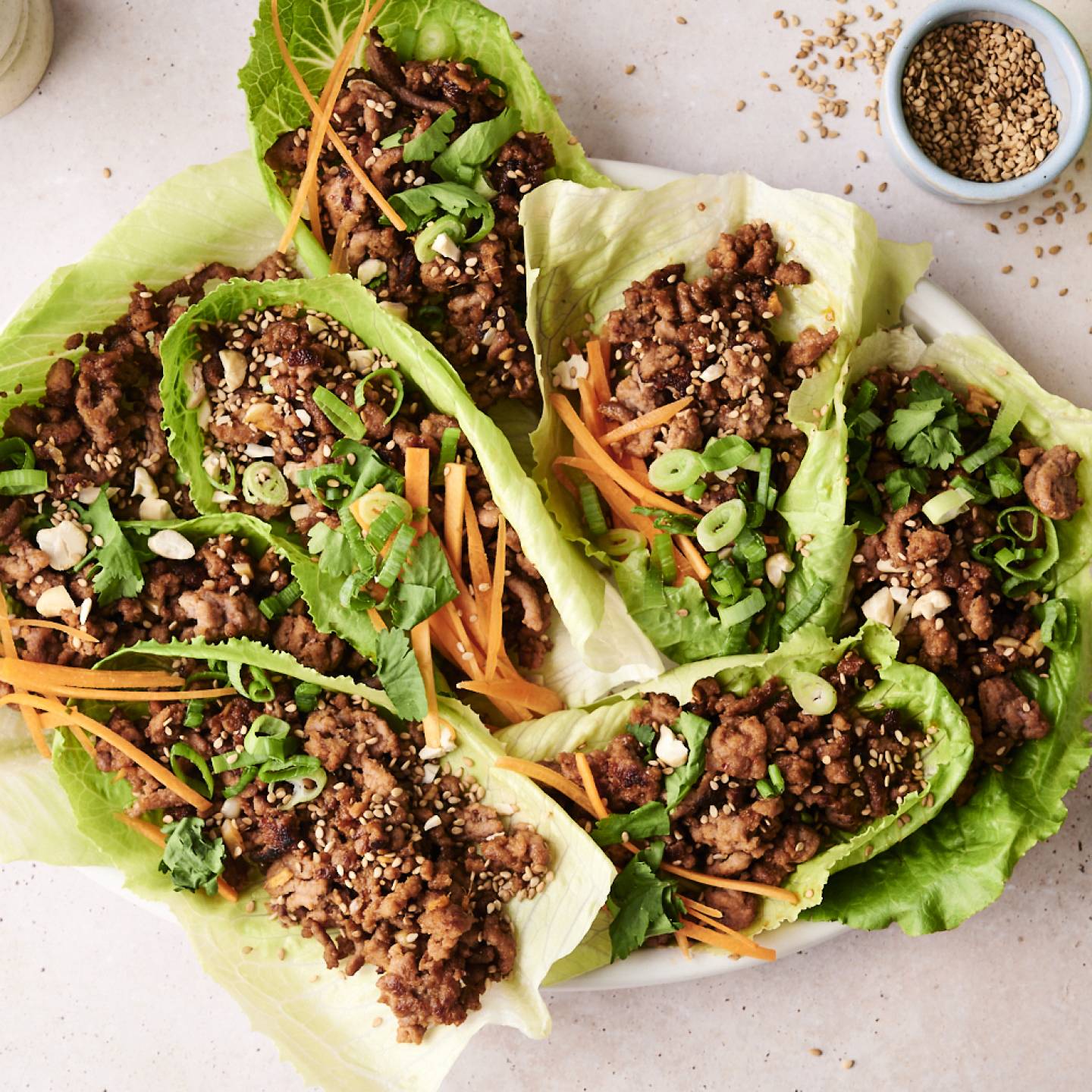 A top-down shot of a plate of Korean beef lettuce wraps and a side of shredded carrots.