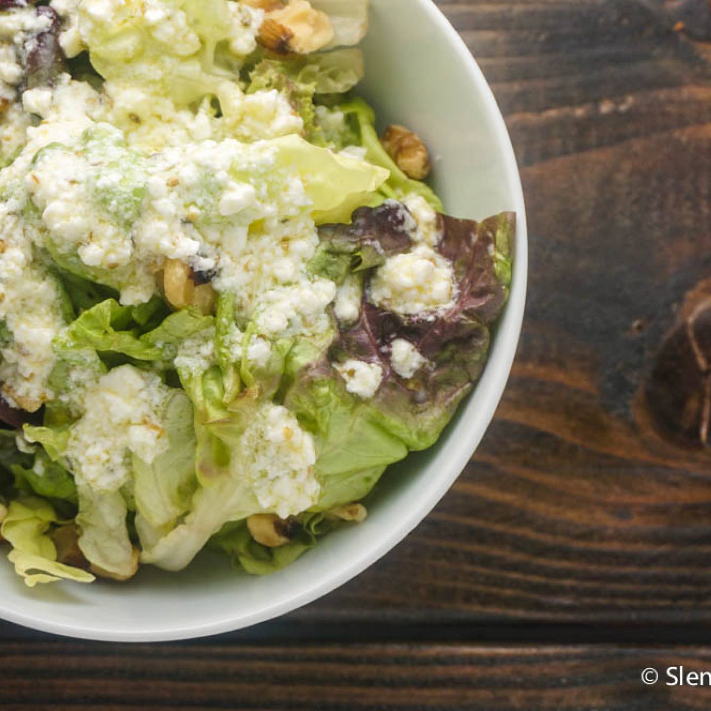 Lemon feta vinaigrette served on a plate of salad greens.