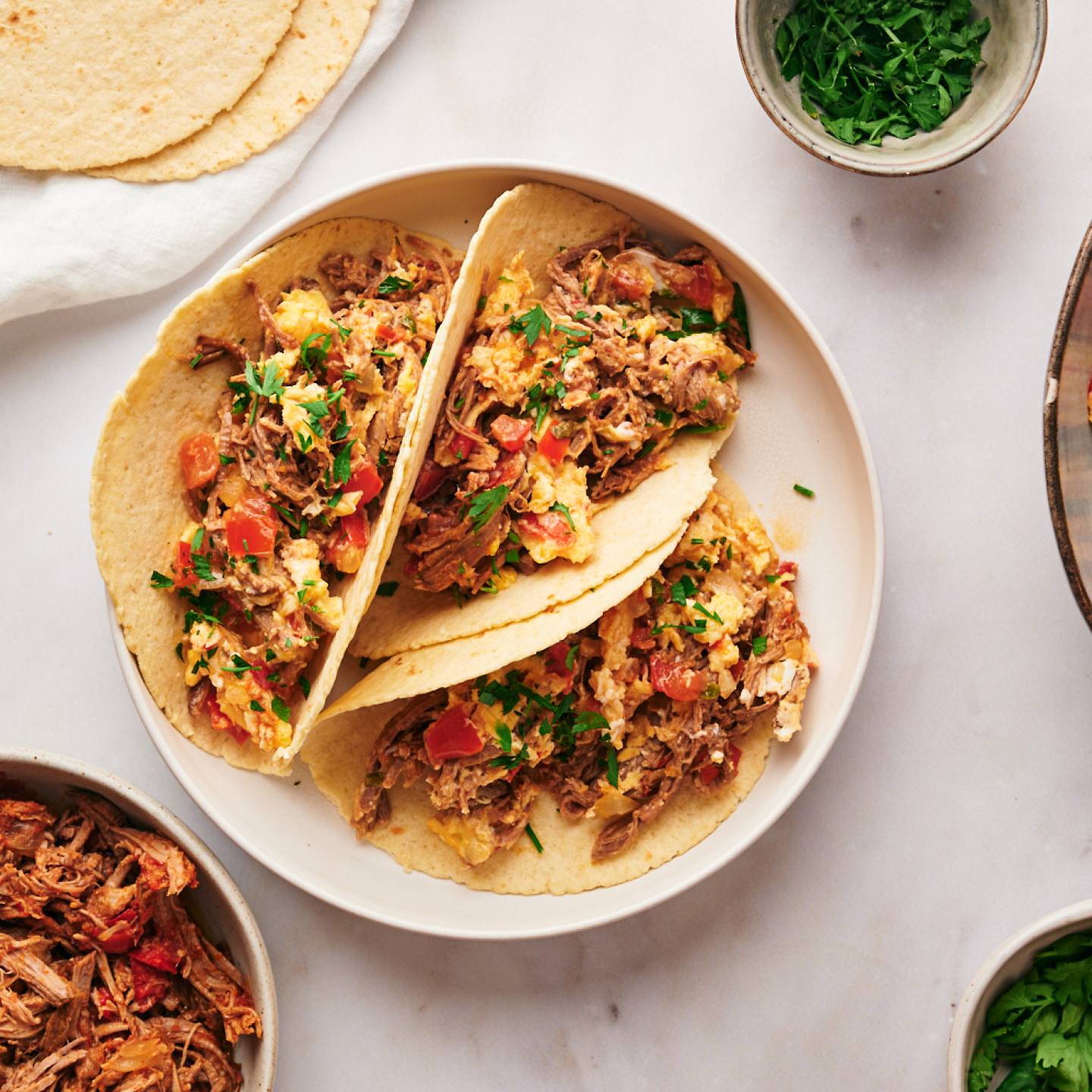 Machaca con huevo with scrambled eggs, beef machaca, tomatoes, onions, jalapeno peppers, and cilantro served in corn tortillas.