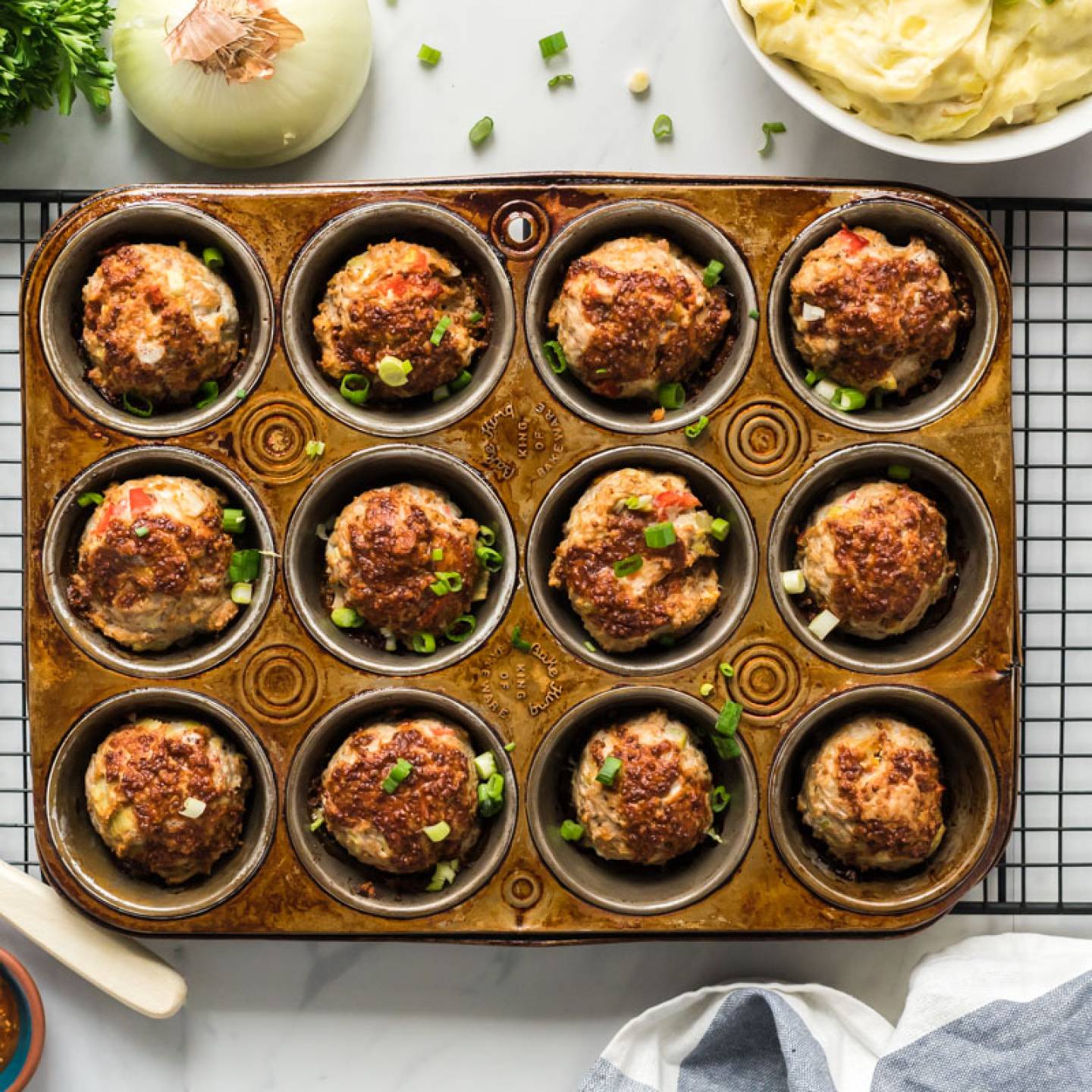 BBQ Meatloaf muffins with ground turkey, red pepper, celery, and a barbecue and mustard sauce in a muffin tin.