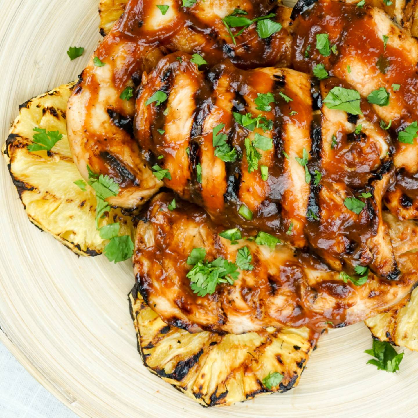 Grilled pineapple chicken with barbecue sauce and grilled pineapple rings.