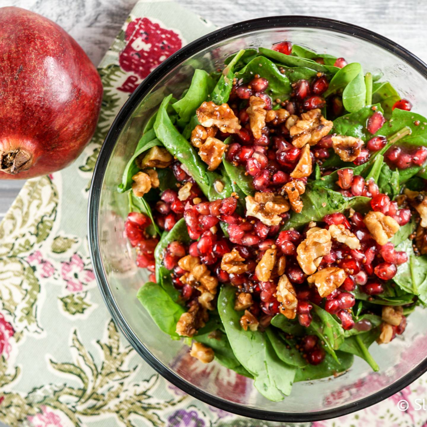 Pomegranate vinaigrette served over a salad with greens, walnuts, and pomegranate arils.