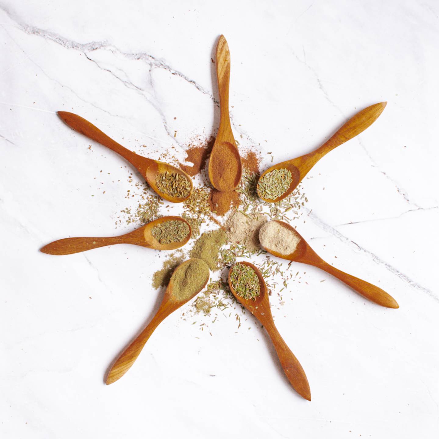 Poultry seasoning on a wooden plate with rosemary, thyme, sage, pepper, garlic, and other spices.