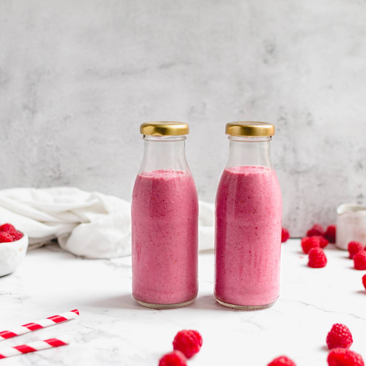 Raspberry chia smoothie with raspberries, chia seeds, almond butter, and almond milk in two glass bottles.