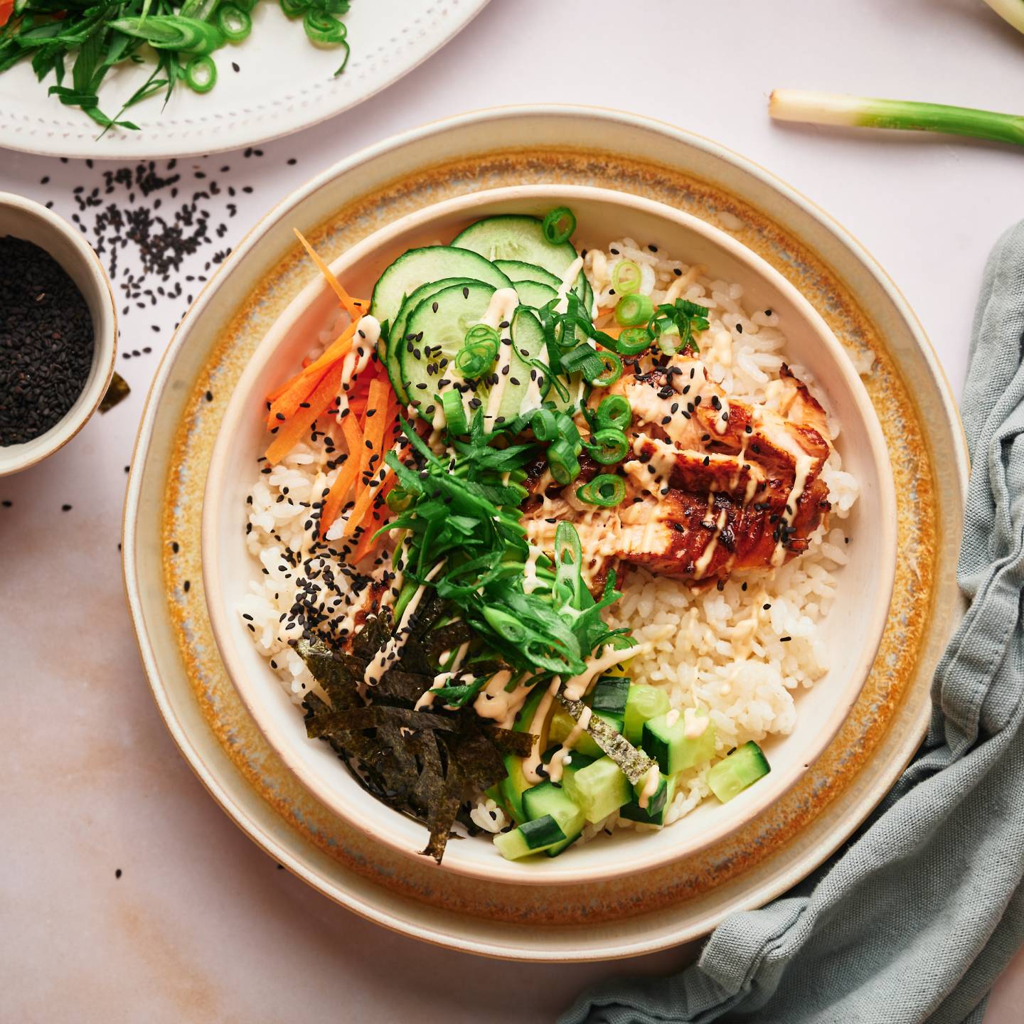 Salmon sushi bowls with sushi rice, salmon, seaweed strips, carrots, cucumbers, and spicy mayo. 