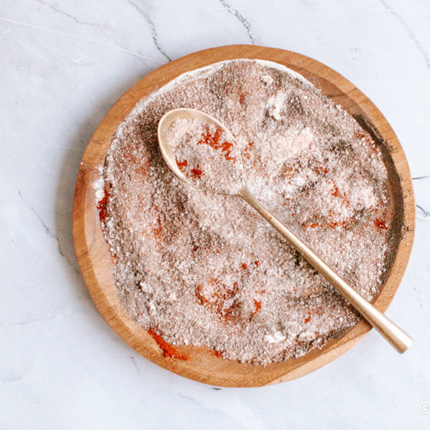 Homemade seasoned salt on a wooden plate with paprika, kosher salt, garlic powder, onion powder, and pepper.