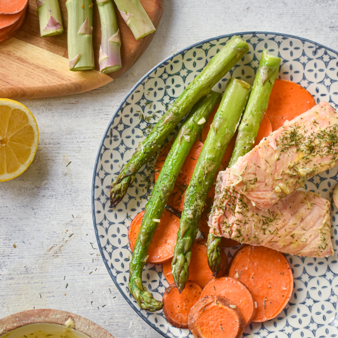 Sheet pan roasted salmon with sweet potatoes and asparagus on a plate with lemon Dijon sauce.