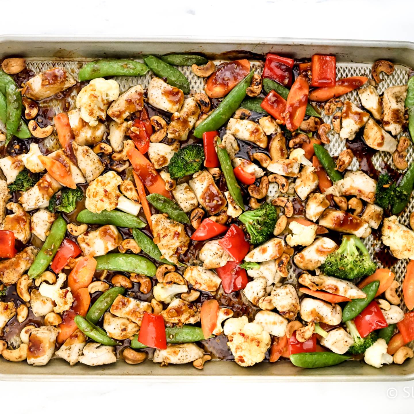 Thai Cashew Chicken with vegetables on a sheet pan.
