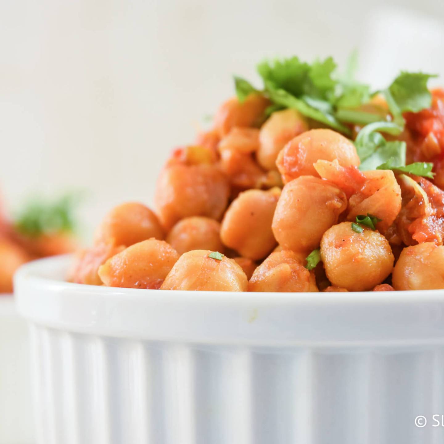 Slow Cooker Chana Masala in a bowl with chickpeas in a curry tomato sauce.