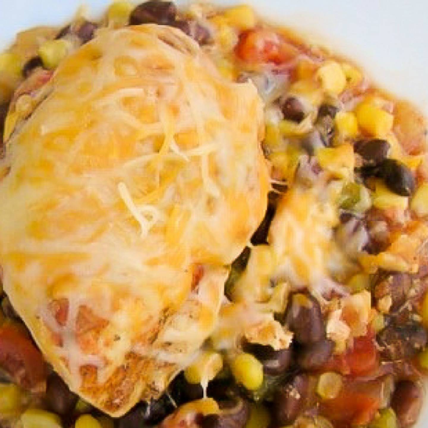 Slow Cooker Southwestern Chicken on a bed of black beans and corn with cheese melted on top.