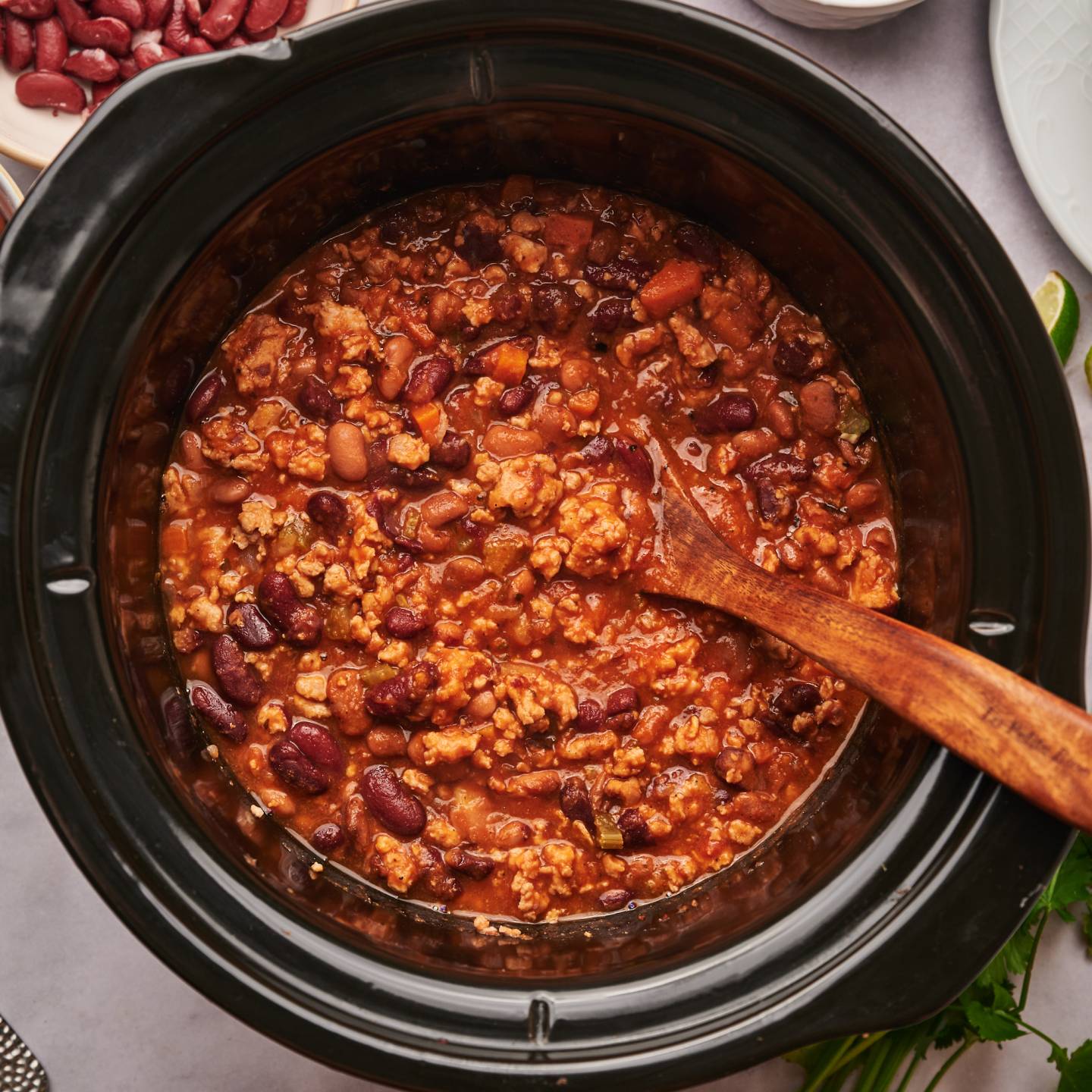 Slow cooker turkey chili with ground turkey, pinto beans, kidney beans, and tomatoes in a slow cooker.