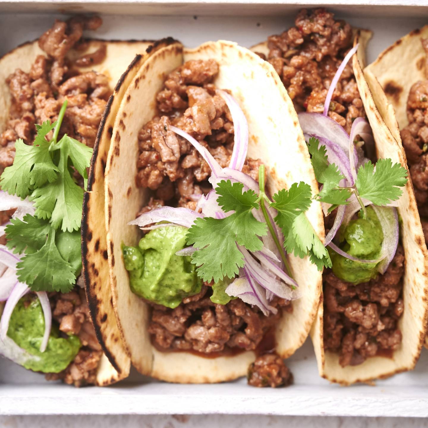 Taco meat served in crispy tortillas with cilantor, onions, and guacamole.