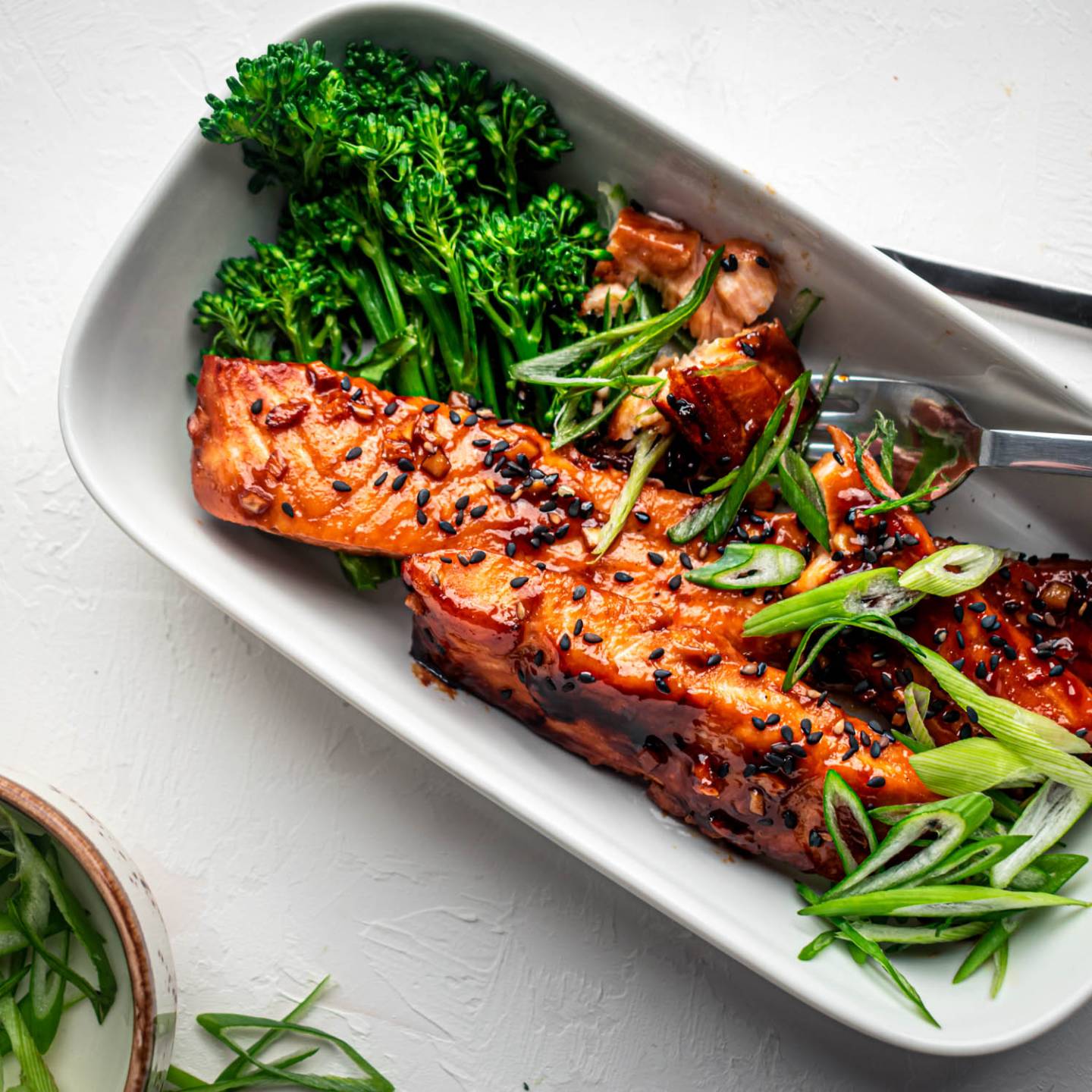 Teriyaki salmon baked in the oven and served with green onions, sesame seeds, and broccoli on the side.