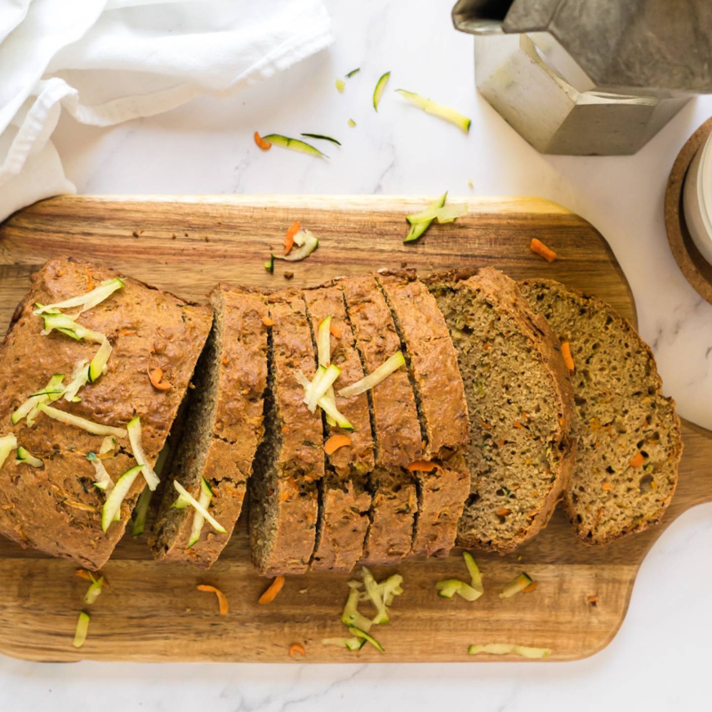 Zucchini carrot bread made with shredded zucchini, carrots, and whole wheat flour sliced on a wooden cutting board.