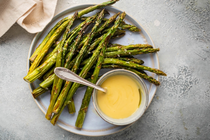 Roasted asparagus on a plate with hollandaise sauce.