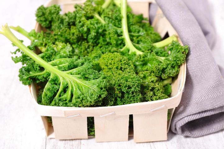 Kale in a wooden basket with a gray napkin.