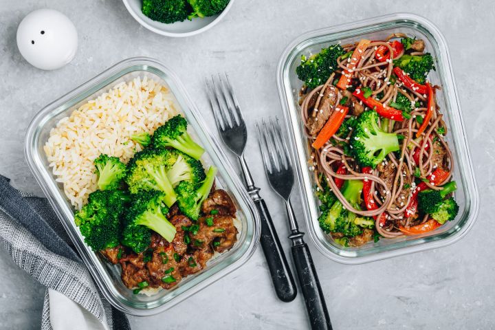 Freezer containers with rice, vegetables, greens, and cooked chicken.