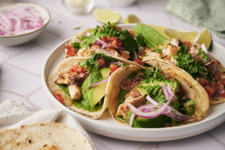 Chicken street tacos with avocado, pickled onions, tomatoes, and grilled chicken.