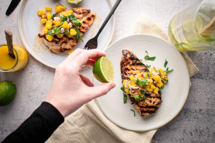 Whole30 grilled chicken with mango salsa and fresh limes on a plate.
