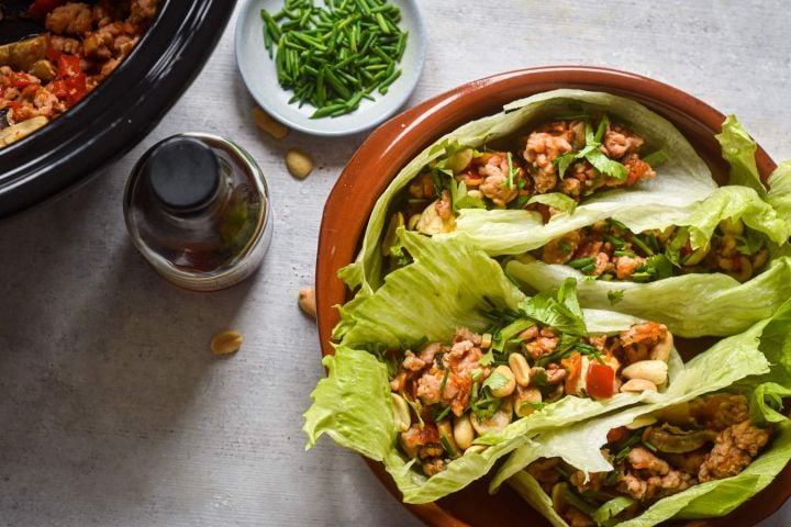 Healthy slow cooker chicken lettuce wraps with red peppers, peanuts, and cilantro.
